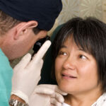 an-ophthalmologist-examines-a-woman's-eye-with-an-ophthalmoscope