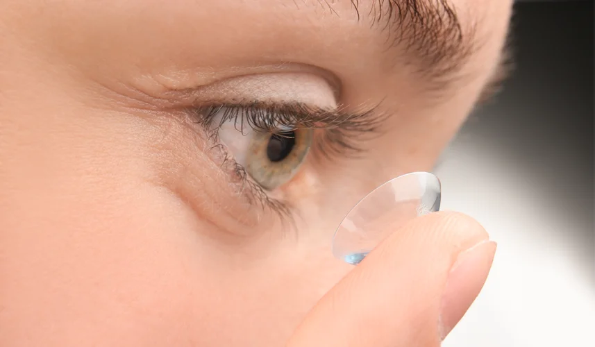 Close-up of a young woman putting contact lens on her eye