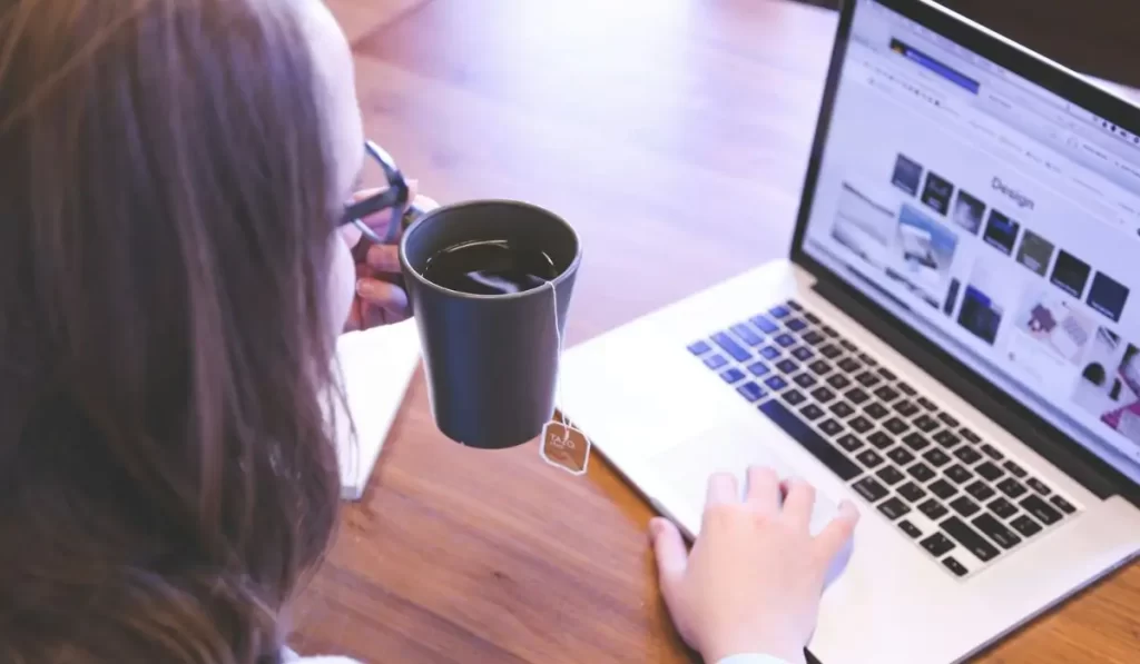 Woman experiencing digital eye strain while working on her laptop, a common cause of bloodshot eyes and headaches.