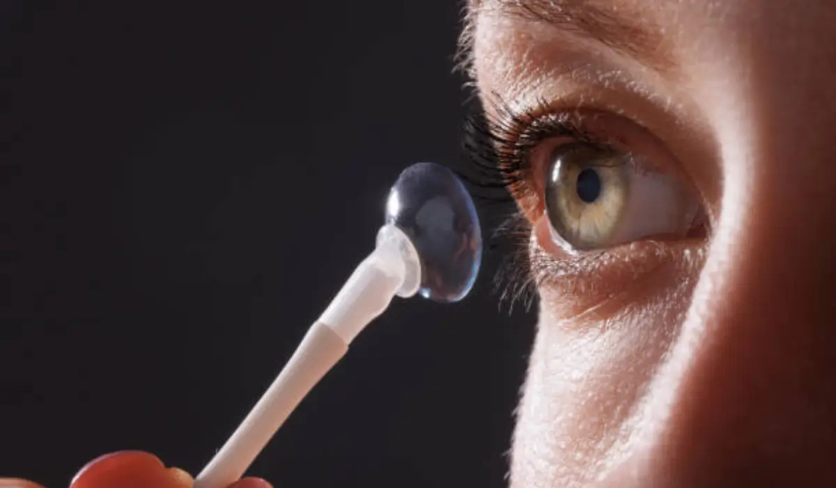 Person using a white insertion tool to apply scleral lenses to the surface of their right eye.