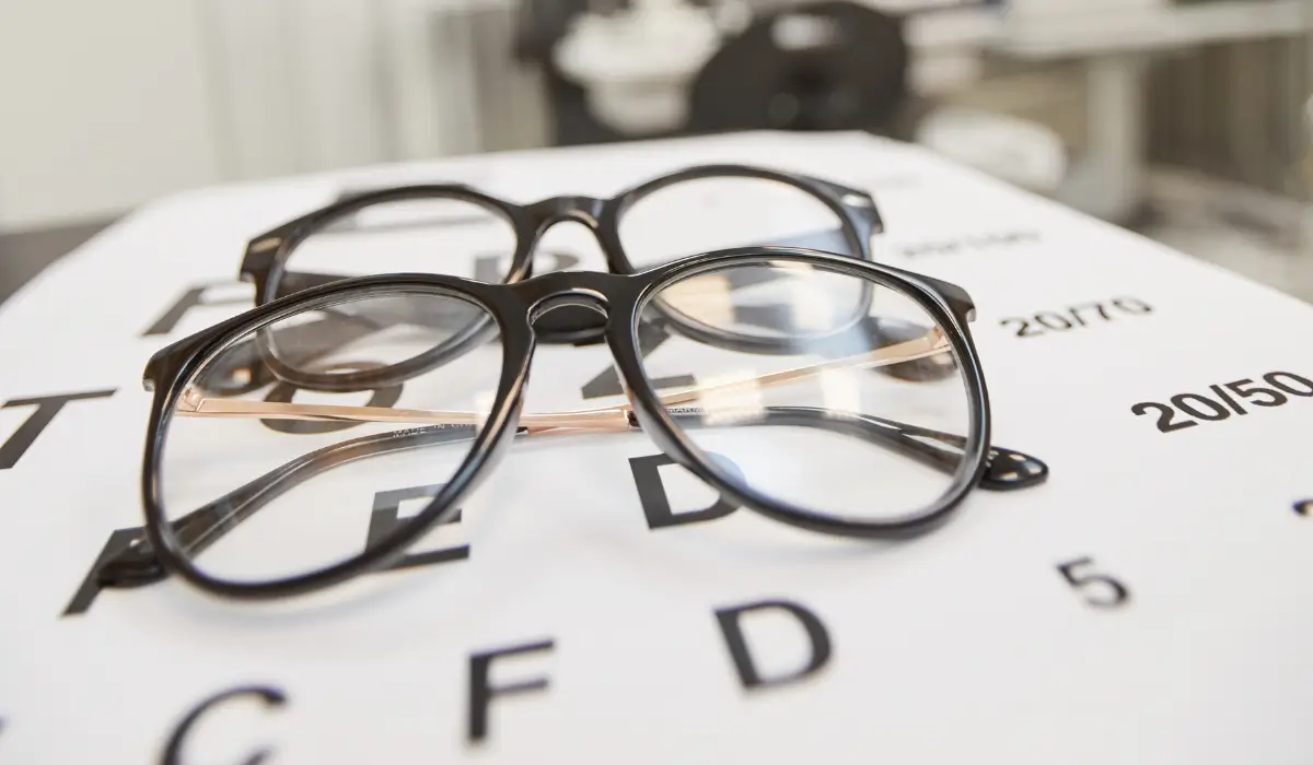 Two pairs of prescription eyeglasses on eye chart after vision insurance-covered routine eye exam visit.